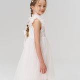 A young girl with braided hair wears KIKI and JOJO's Girls Daisy Crystal Flower Hair Clips (set of 6) and a white ruffled dress, standing sideways and looking at the camera against a plain light background.