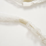 Close-up of white lace straps with elastic sections on a plain background—an elegant detail from the KIKI and JOJO Girls Pearl Lace Ribbon Headband, ideal as a flower girl accessory or paired with handcrafted pieces.