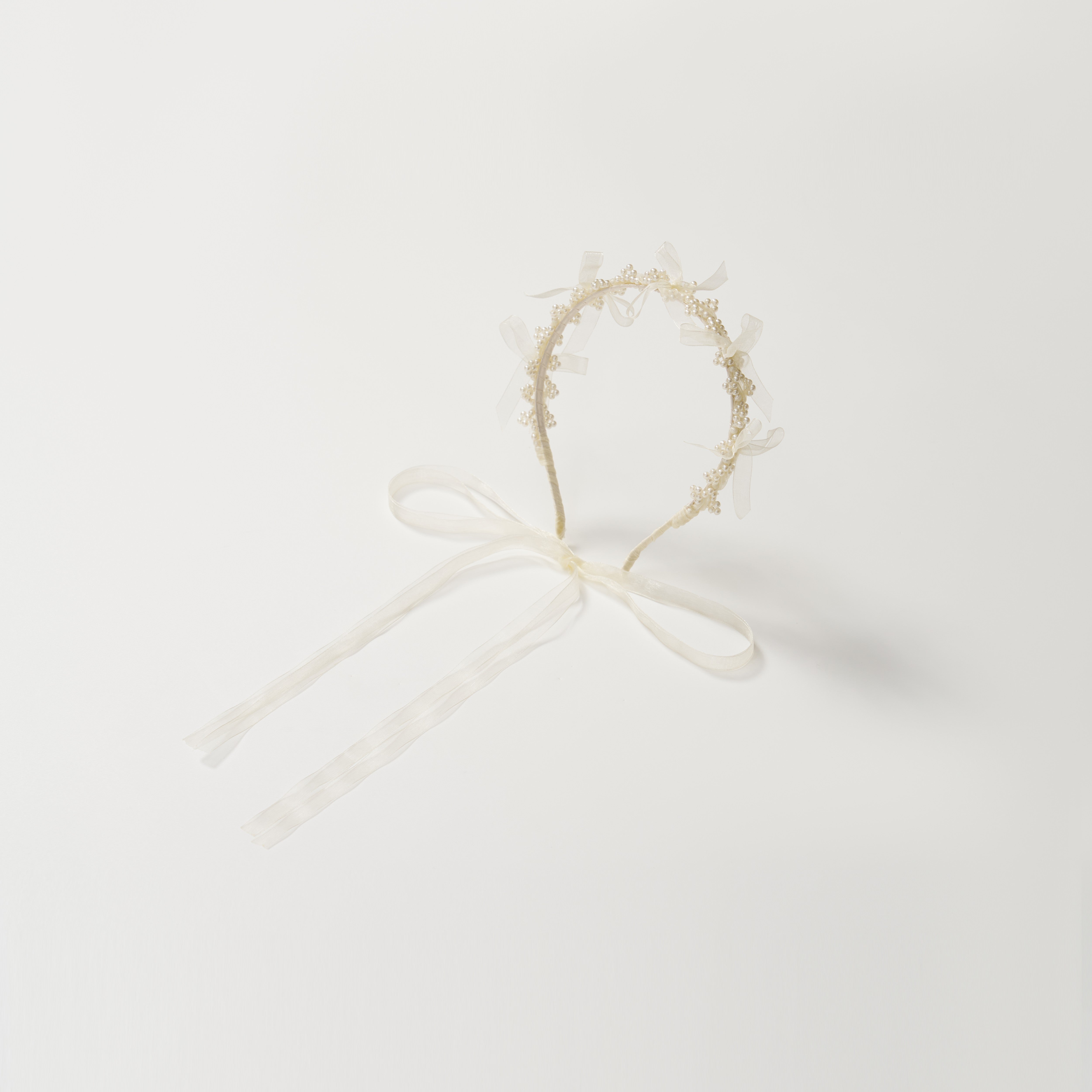 The KIKI and JOJO Girls Pearl Bow Crown Headband features delicate pearls and an elegant white bow, presented against a plain white background.