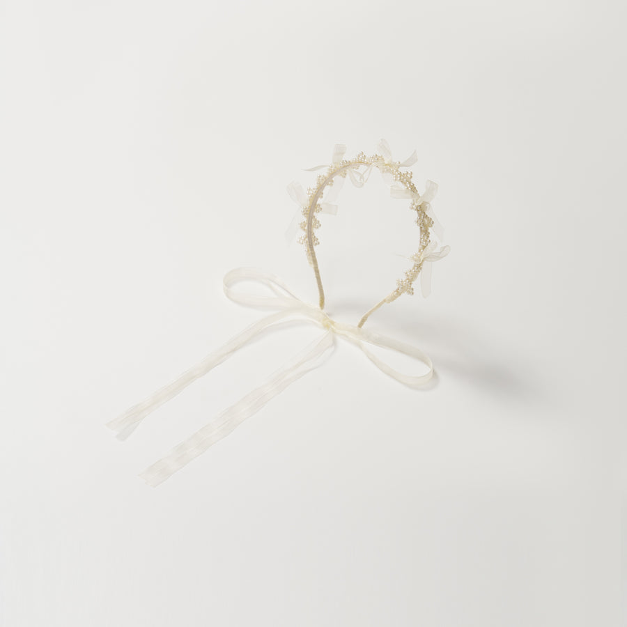 The KIKI and JOJO Girls Pearl Bow Crown Headband features delicate pearls and an elegant white bow, presented against a plain white background.