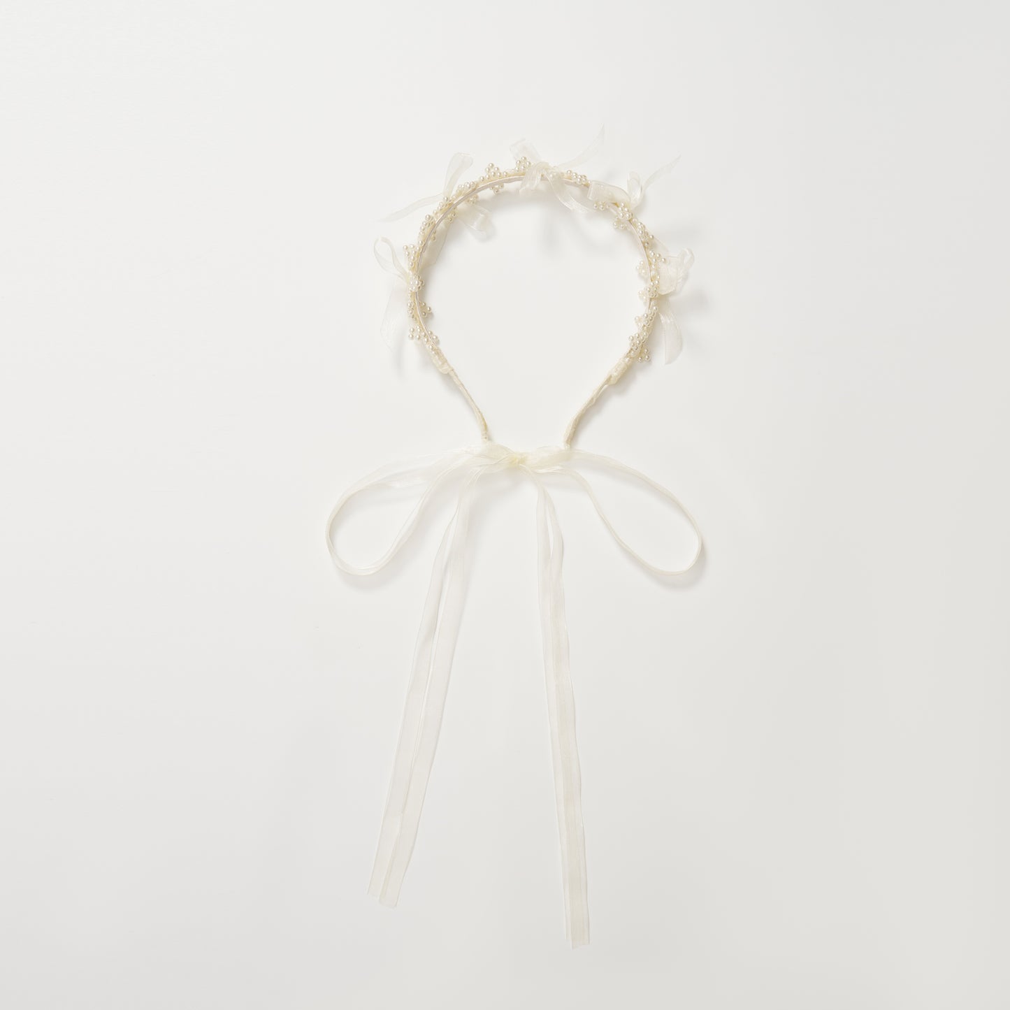 The KIKI and JOJO Girls Pearl Bow Crown Headband features delicate organza bows and white ribbon ties, arranged in a circular shape on a plain white background.