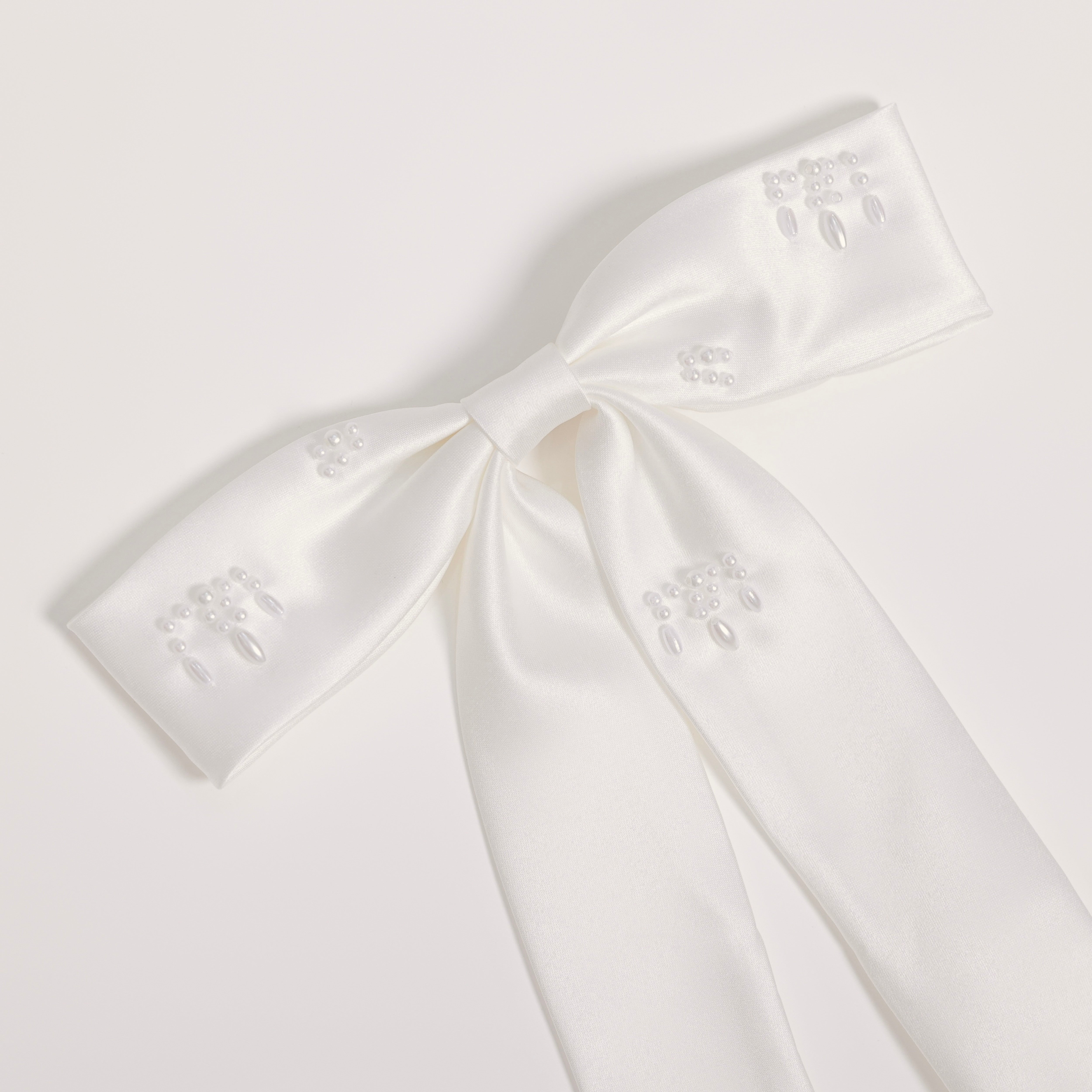 The Girls Hand-Beaded Pearl Satin Bow Hair Clip by KIKI and JOJO features embroidered patterns and beaded details on each loop and tail, making it a perfect flower girl accessory. Shown against a light plain background.