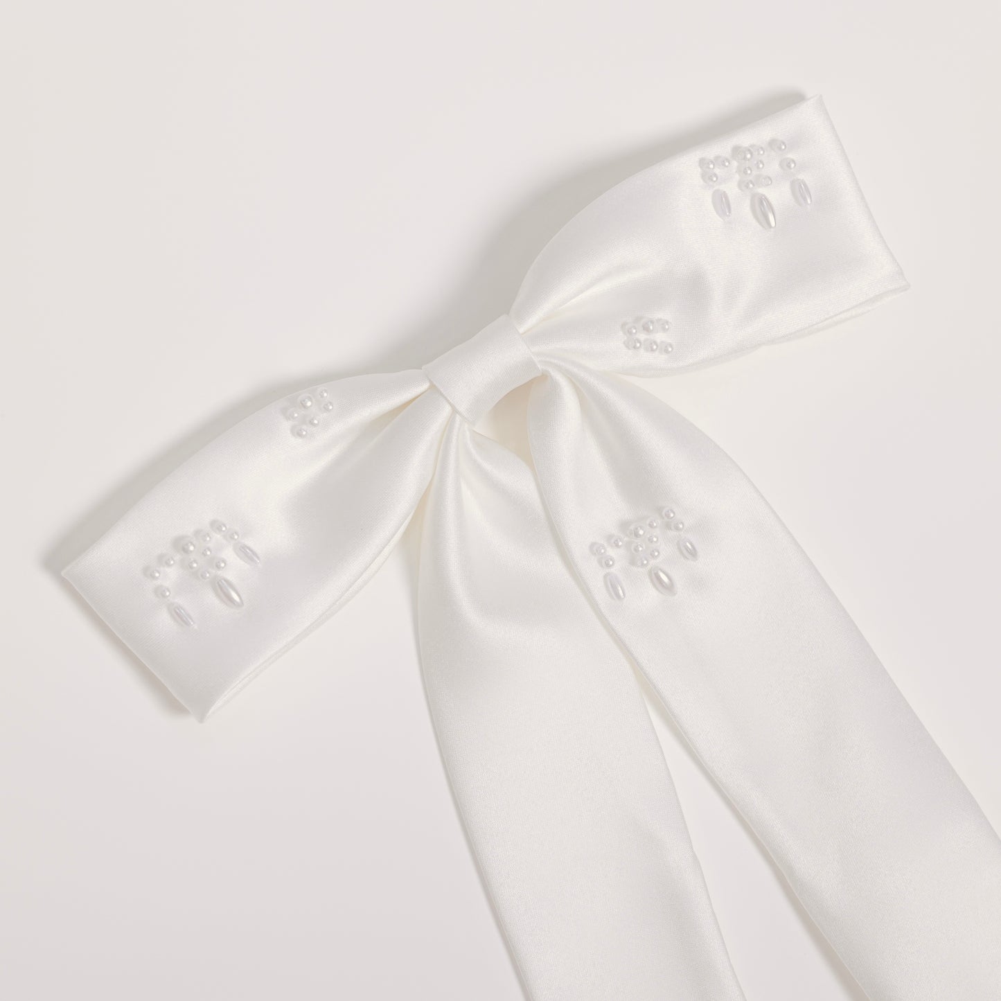 The Girls Hand-Beaded Pearl Satin Bow Hair Clip by KIKI and JOJO features embroidered patterns and beaded details on each loop and tail, making it a perfect flower girl accessory. Shown against a light plain background.