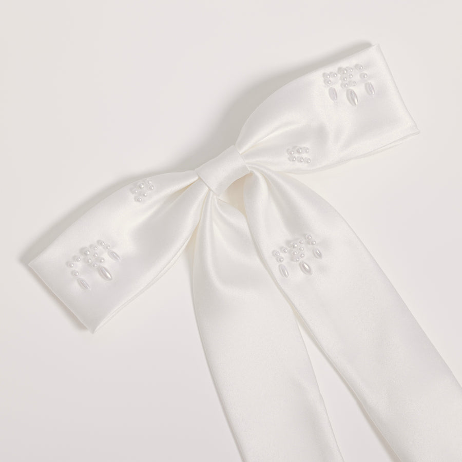 The Girls Hand-Beaded Pearl Satin Bow Hair Clip by KIKI and JOJO features embroidered patterns and beaded details on each loop and tail, making it a perfect flower girl accessory. Shown against a light plain background.