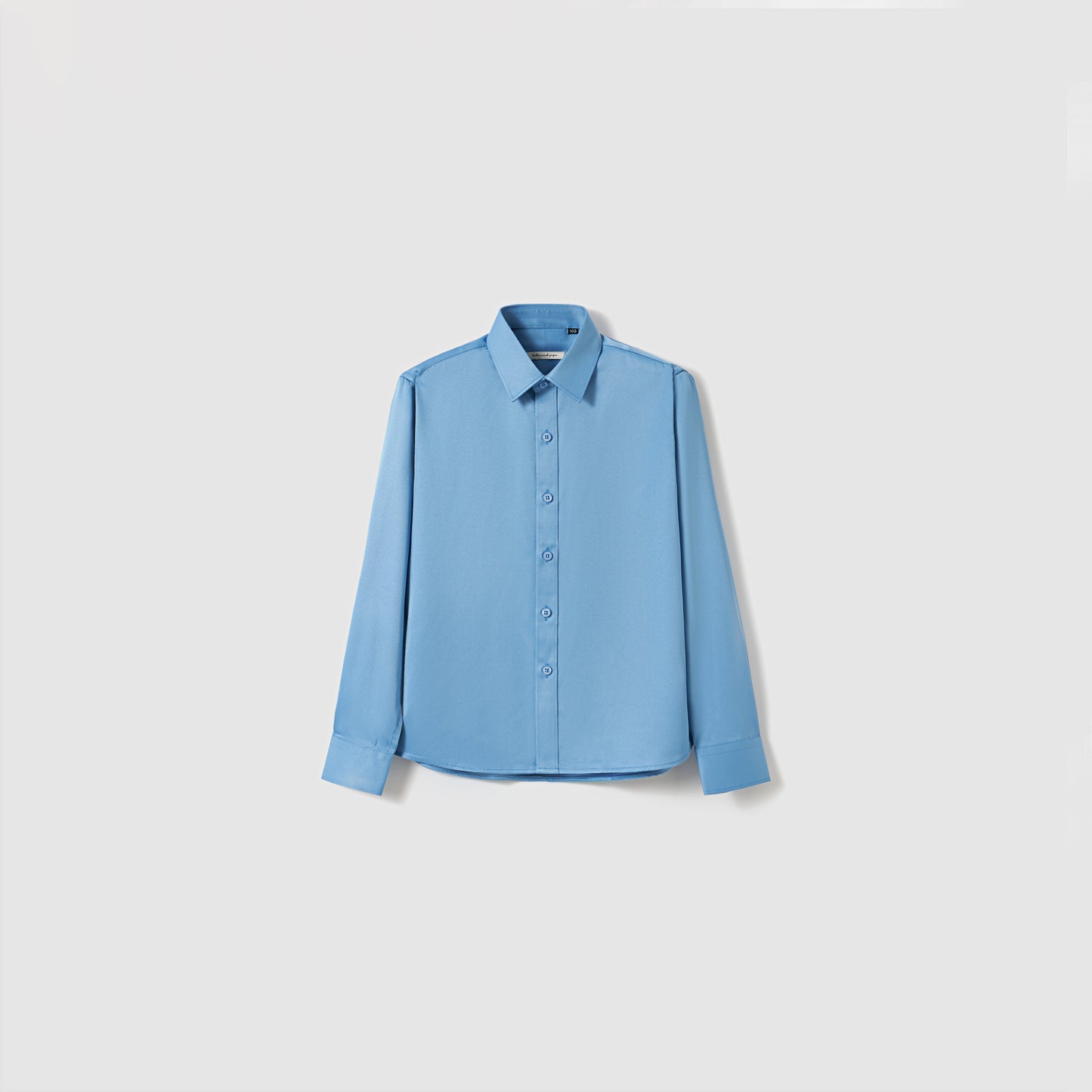 The Boys Sky Blue Dress Shirt by KIKI and JOJO features long sleeves and a classic collar, shown against a plain white background.
