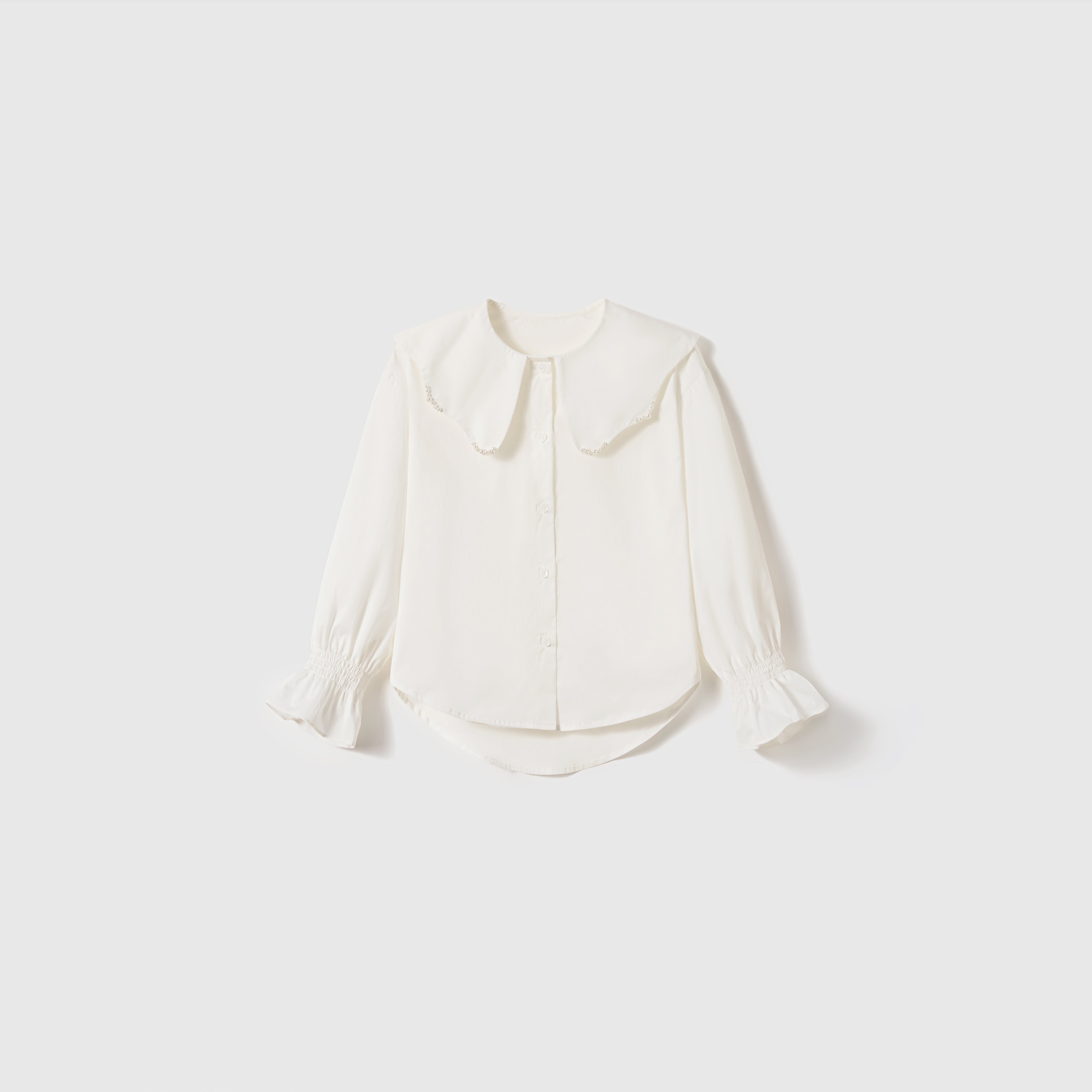 The Moonlit Whisper Blouse by KIKI and JOJO is a white vintage long-sleeve top with a wide Peter Pan collar, puffed lantern sleeves, and ruffled cuffs, shown against a plain light background.