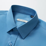 Close-up of the KIKI and JOJO Boys Sky Blue Dress Shirt, showing buttons and the brand label inside the collar, set against a white background.