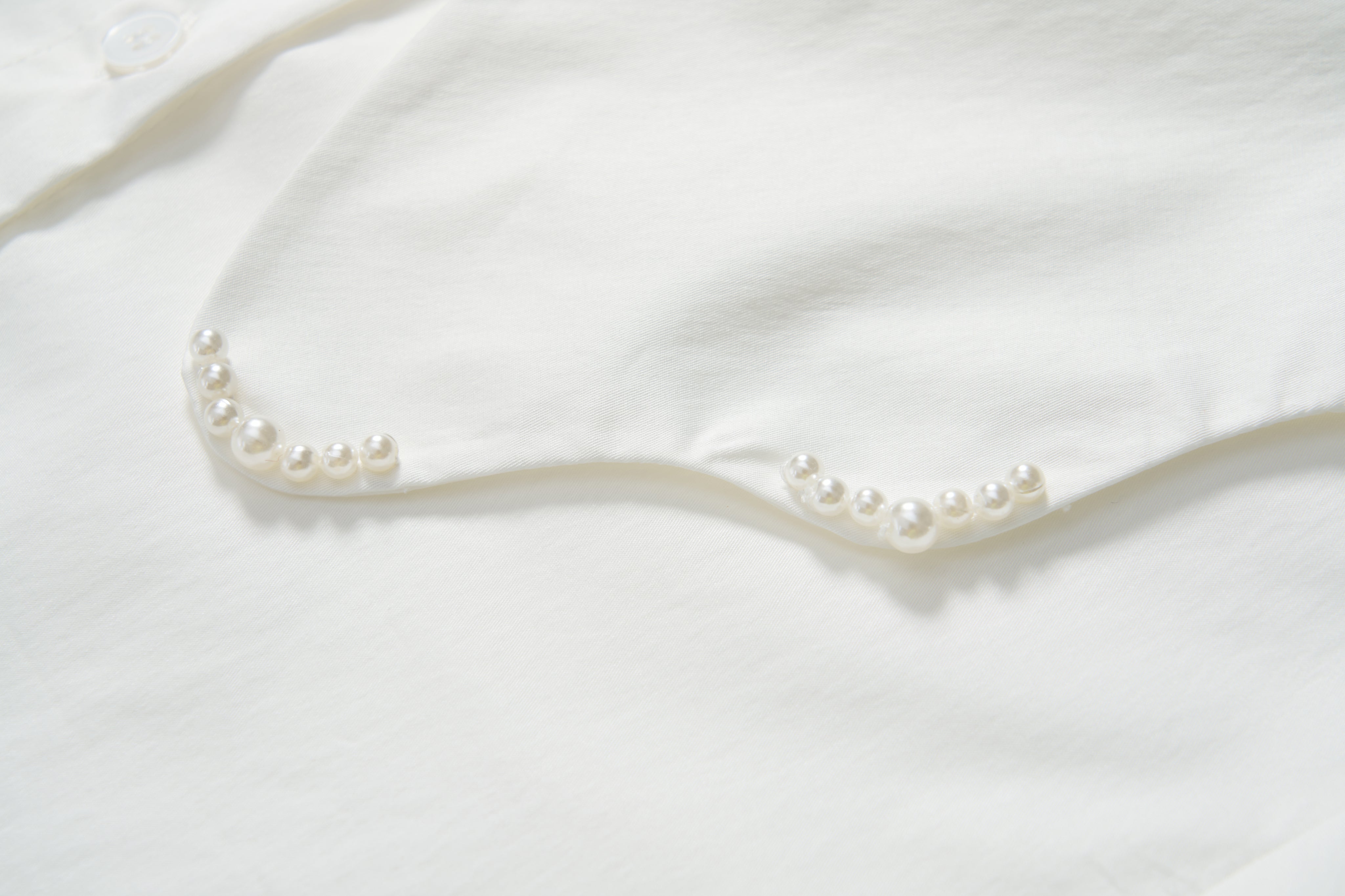 Close-up of the Moonlit Whisper Blouse by KIKI and JOJO, showcasing pearl embellishments along the scalloped collar.