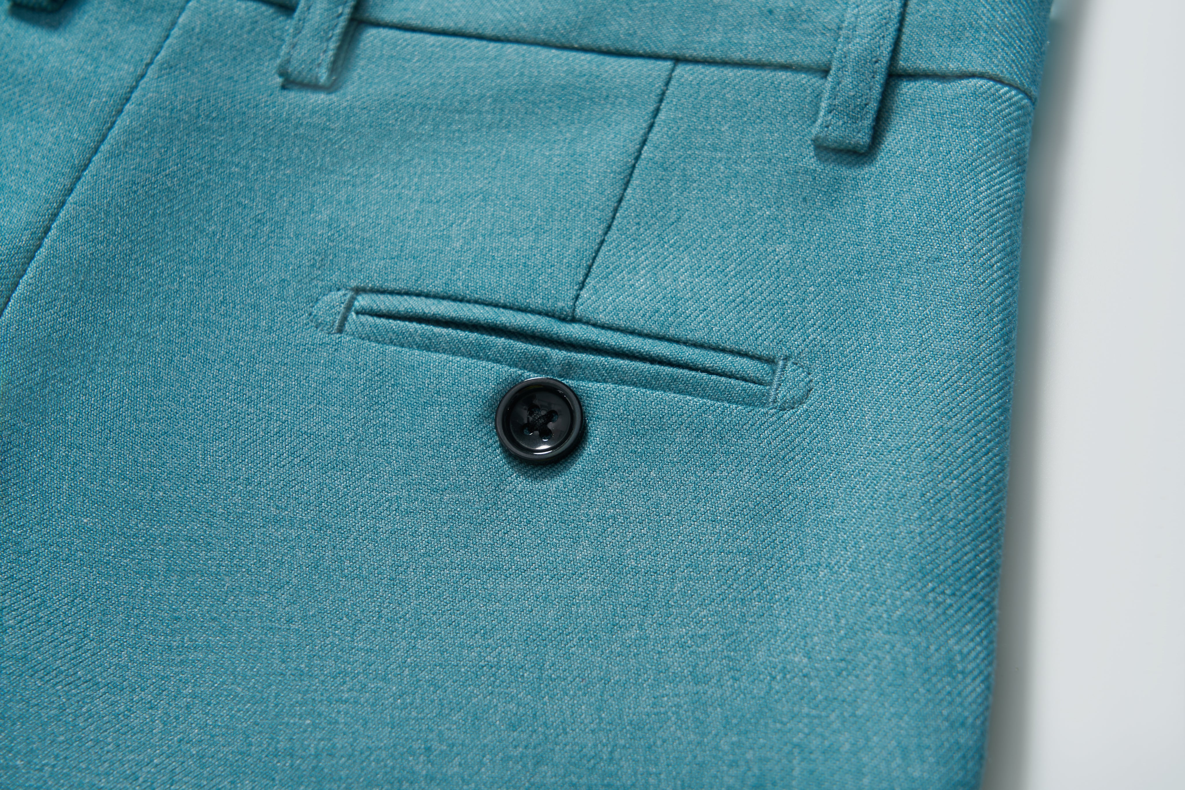 Close-up of the turquoise pocket with button on KIKI and JOJO's Celeste Whimsy Suit Pants for boys, featuring an adjustable waistband for a perfect fit.