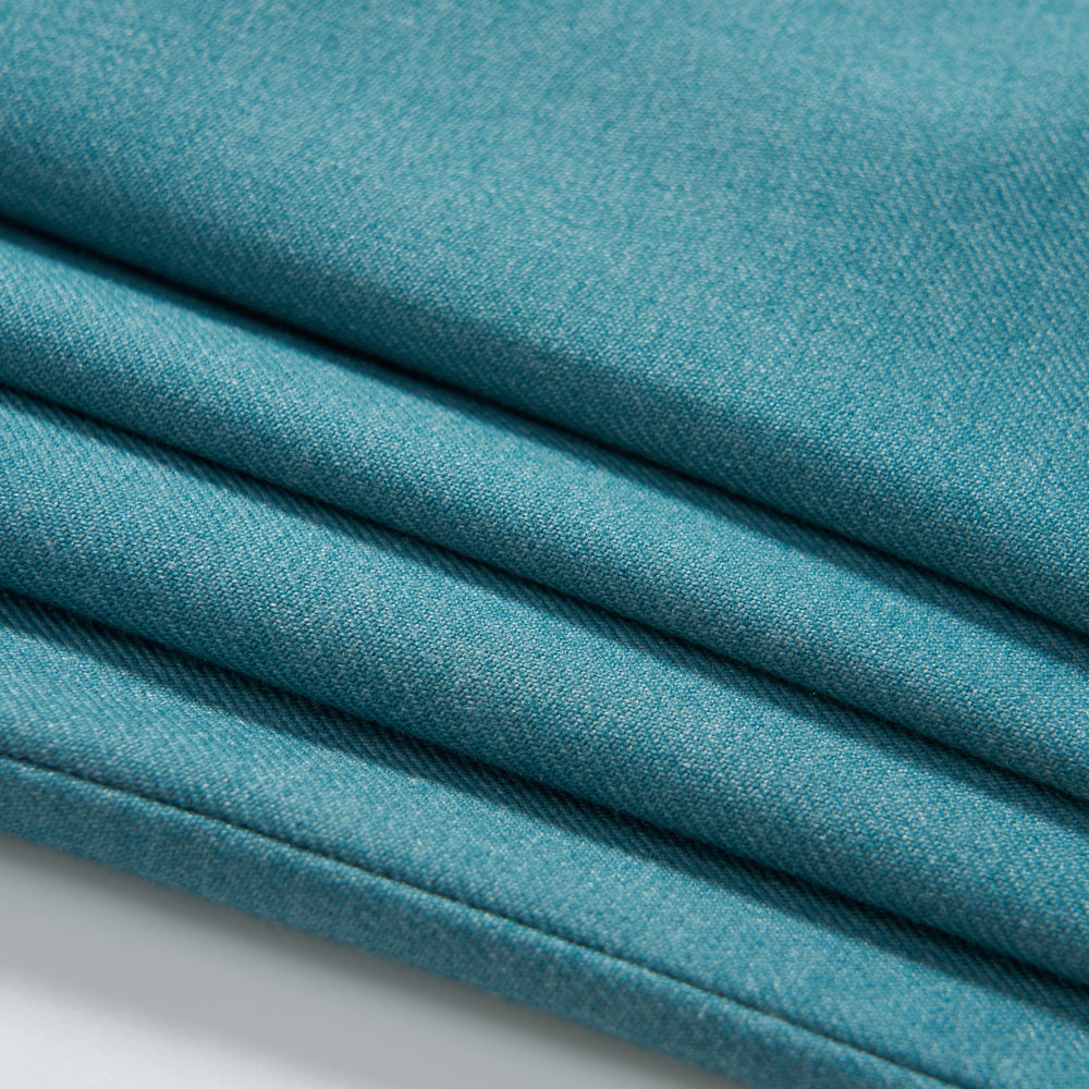 Close-up of four neatly folded layers of turquoise fabric with a smooth texture for KIKI and JOJO's Celeste Whimsy Suit Pants, ideal for boys featuring an adjustable waistband, displayed on a white surface.