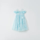 The Feathered Whisper Dress - Blue by KIKI and JOJO is a light blue, sleeveless, knee-length dress with a tulle skirt and floral appliqué, radiating ethereal elegance against a plain white background.