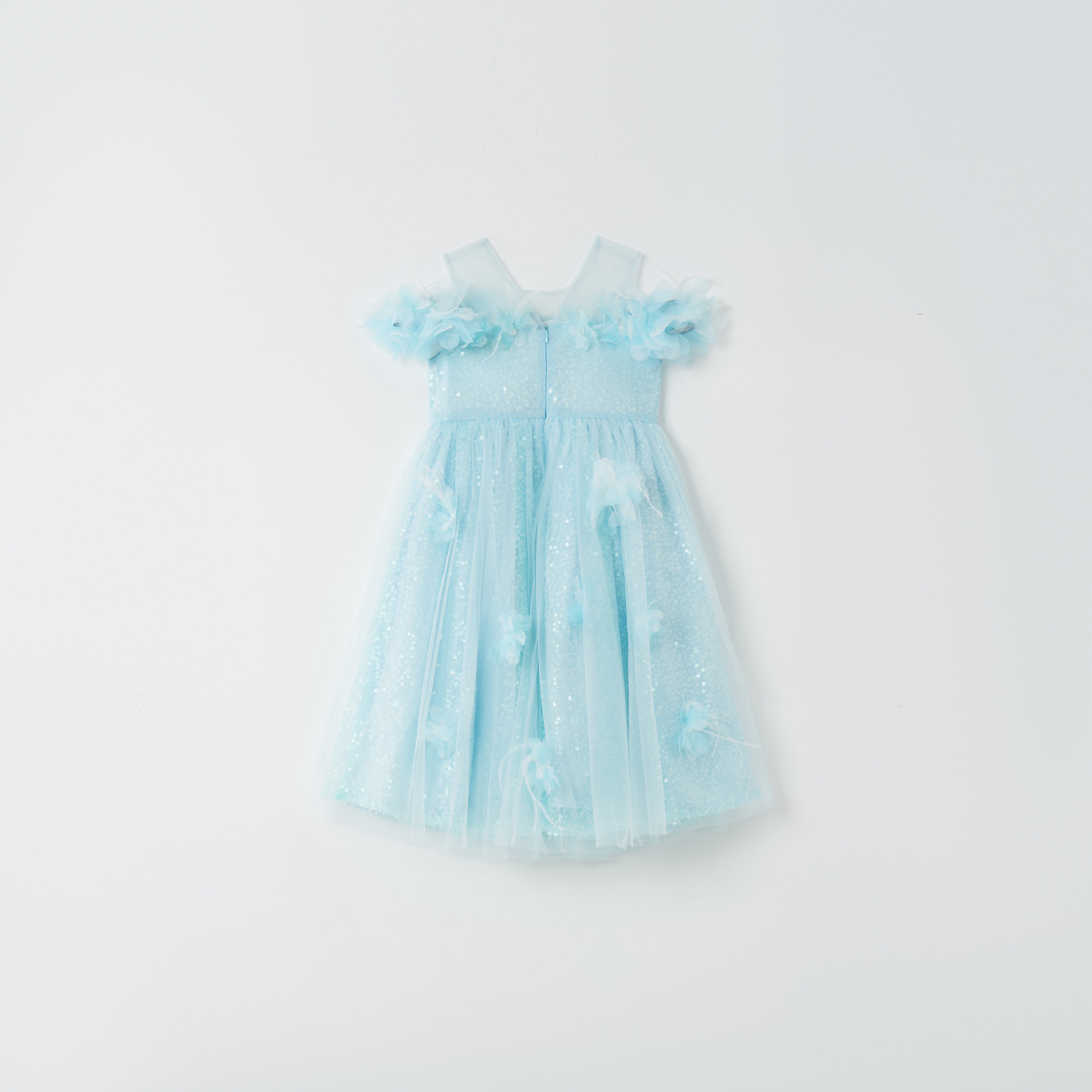 The Feathered Whisper Dress - Blue by KIKI and JOJO is a light blue, sleeveless, knee-length dress with a tulle skirt and floral appliqué, radiating ethereal elegance against a plain white background.