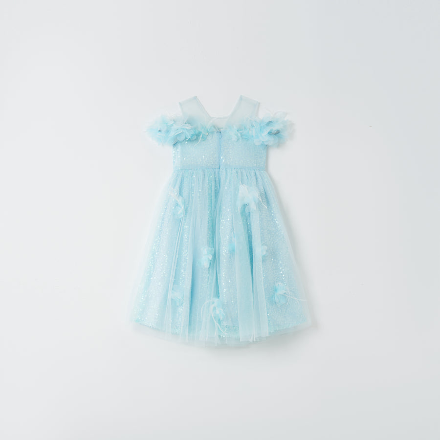 The Feathered Whisper Dress - Blue by KIKI and JOJO is a light blue, sleeveless, knee-length dress with a tulle skirt and floral appliqué, radiating ethereal elegance against a plain white background.