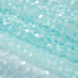 Close-up of the Feathered Whisper Dress - Blue by KIKI and JOJO, featuring pale blue sheer fabric adorned with round iridescent sequins for a shimmering, ethereal look—ideal for an off-shoulder statement.