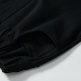 Close-up of the Petal Whisper Dress Pants by KIKI and JOJO, featuring a flared black design, elastic waistband, snap button, and side pocket. Crafted from stretchy fabric and displayed flat on a white background.