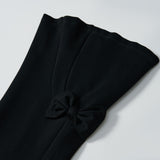Close-up of the black stretchy sleeve of KIKI and JOJO's Petal Whisper Dress Pants, featuring a small pleat and decorative bow near the cuff, set against a plain white background.