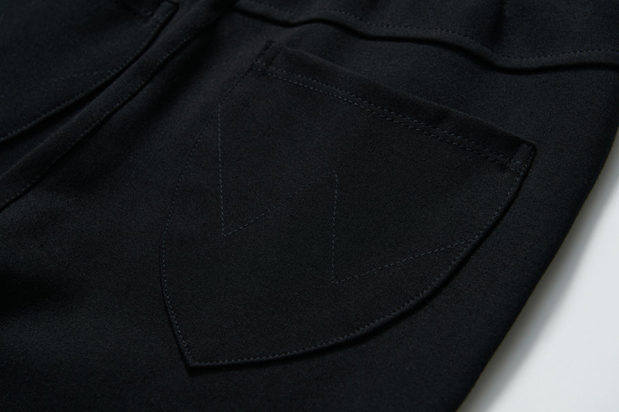 Close-up of a Petal Whisper Dress Pants pocket by KIKI and JOJO, featuring a black stretchy fabric with visible "W" pattern stitching on the flap.