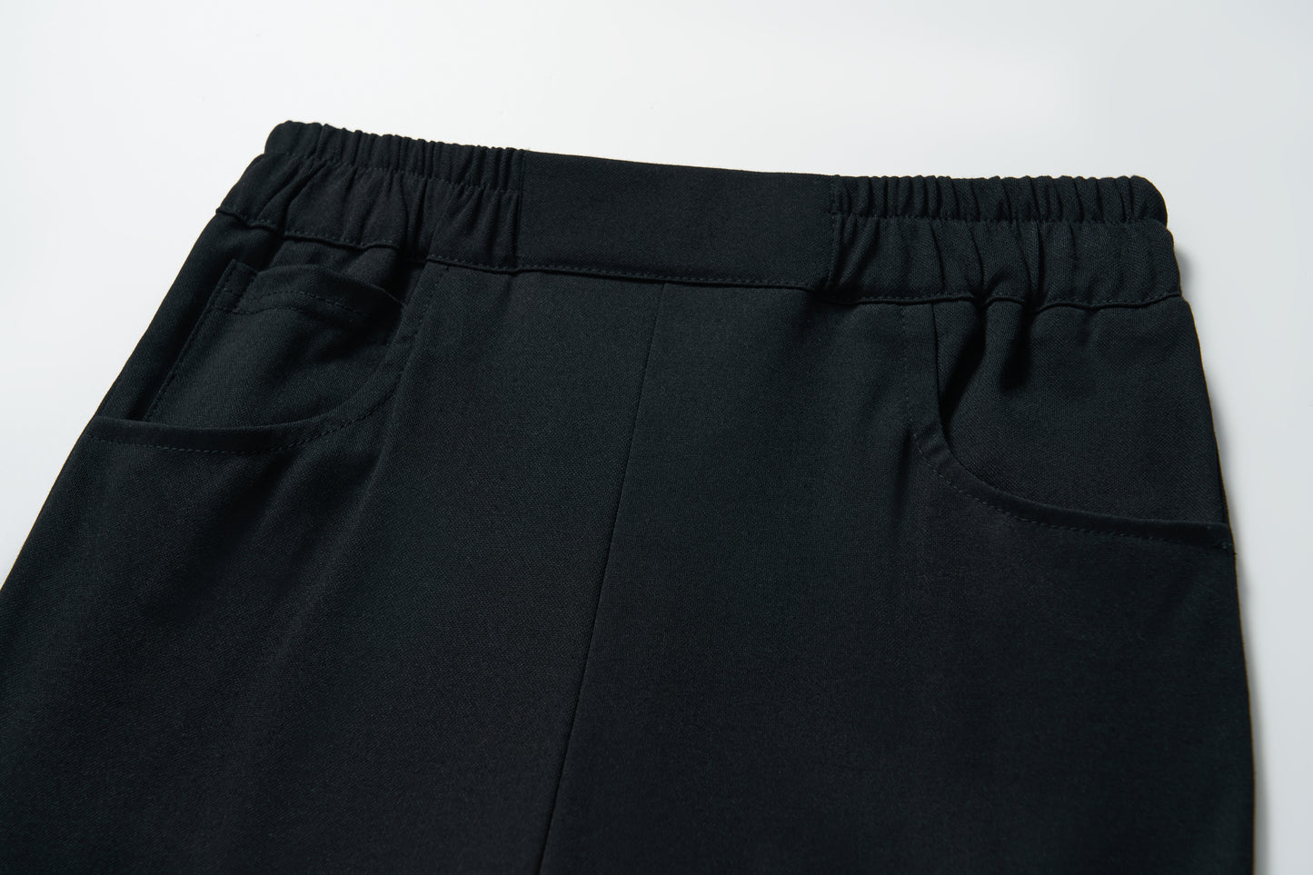 Close-up of KIKI and JOJO’s Echo Whisper Dress Pants featuring a flared black design, elastic waistband, and two side pockets, shown on a white background.