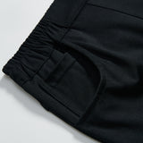 Close-up of the elastic waistband and pocket on KIKI and JOJO's Echo Whisper Dress Pants, showing off the smooth fabric, stitched seams, and flared black design.