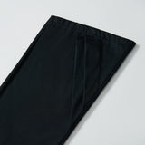 A close-up of the hem of KIKI and JOJO’s Echo Whisper Dress Pants in black, laid flat on a white surface, showcases their clean flared design.