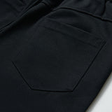 Close-up of the back pocket on KIKI and JOJO Echo Whisper Dress Pants, featuring detailed stitching and an elastic waistband on these flared black pants.