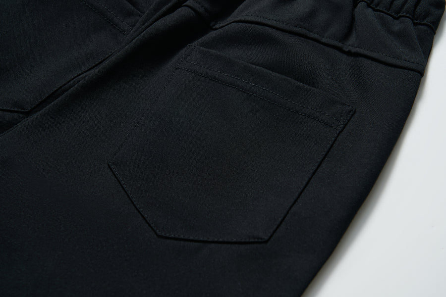 Close-up of the back pocket on KIKI and JOJO Echo Whisper Dress Pants, featuring detailed stitching and an elastic waistband on these flared black pants.