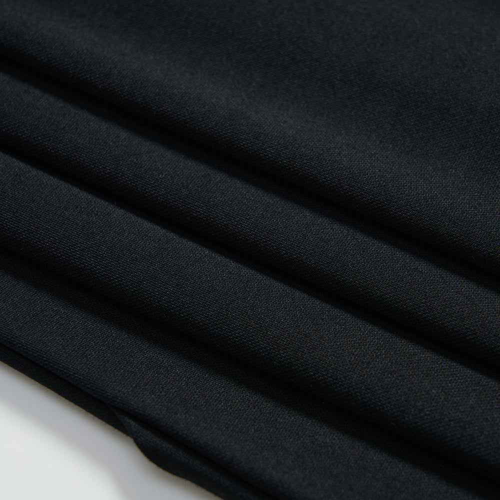 Close-up of neatly folded dark fabric with a smooth texture, showing four visible folds against a white background.