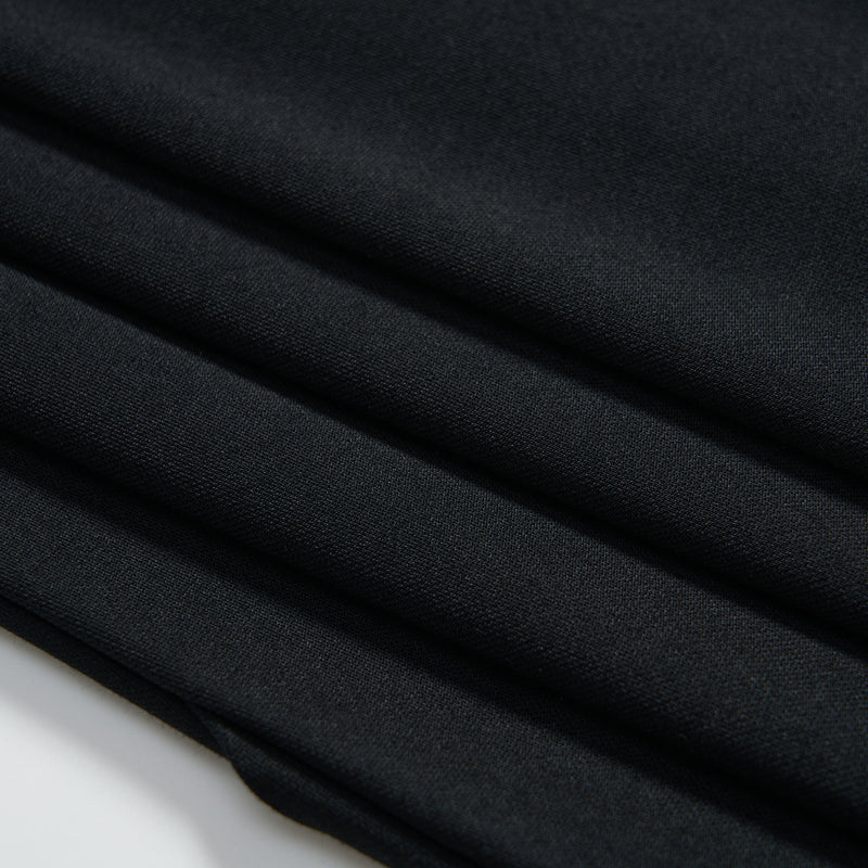 Close-up of neatly folded dark fabric with a smooth texture, showing four visible folds against a white background.