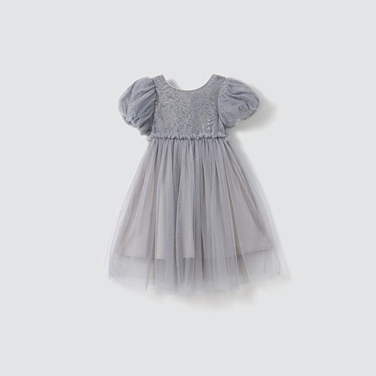 The Dusk Whisper Dress by KIKI and JOJO features light gray glittering tulle, short puff sleeves, a lace bodice, and a layered skirt, displayed on a plain background.