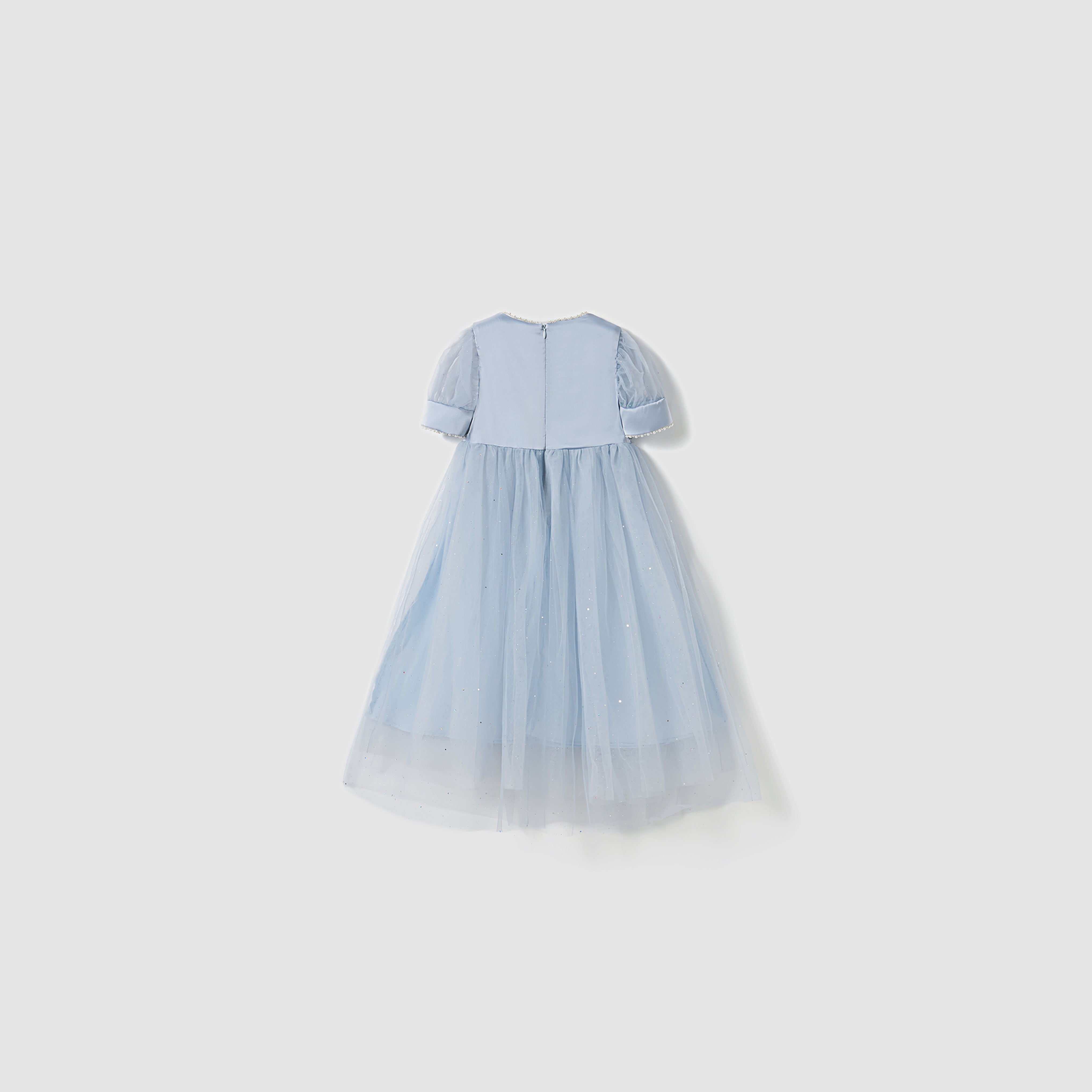 The Mist Whisper Dress by KIKI and JOJO is shown flat on a white background. This light blue A-line dress has short sleeves, an ankle-length tulle skirt, and delicate embellishments.