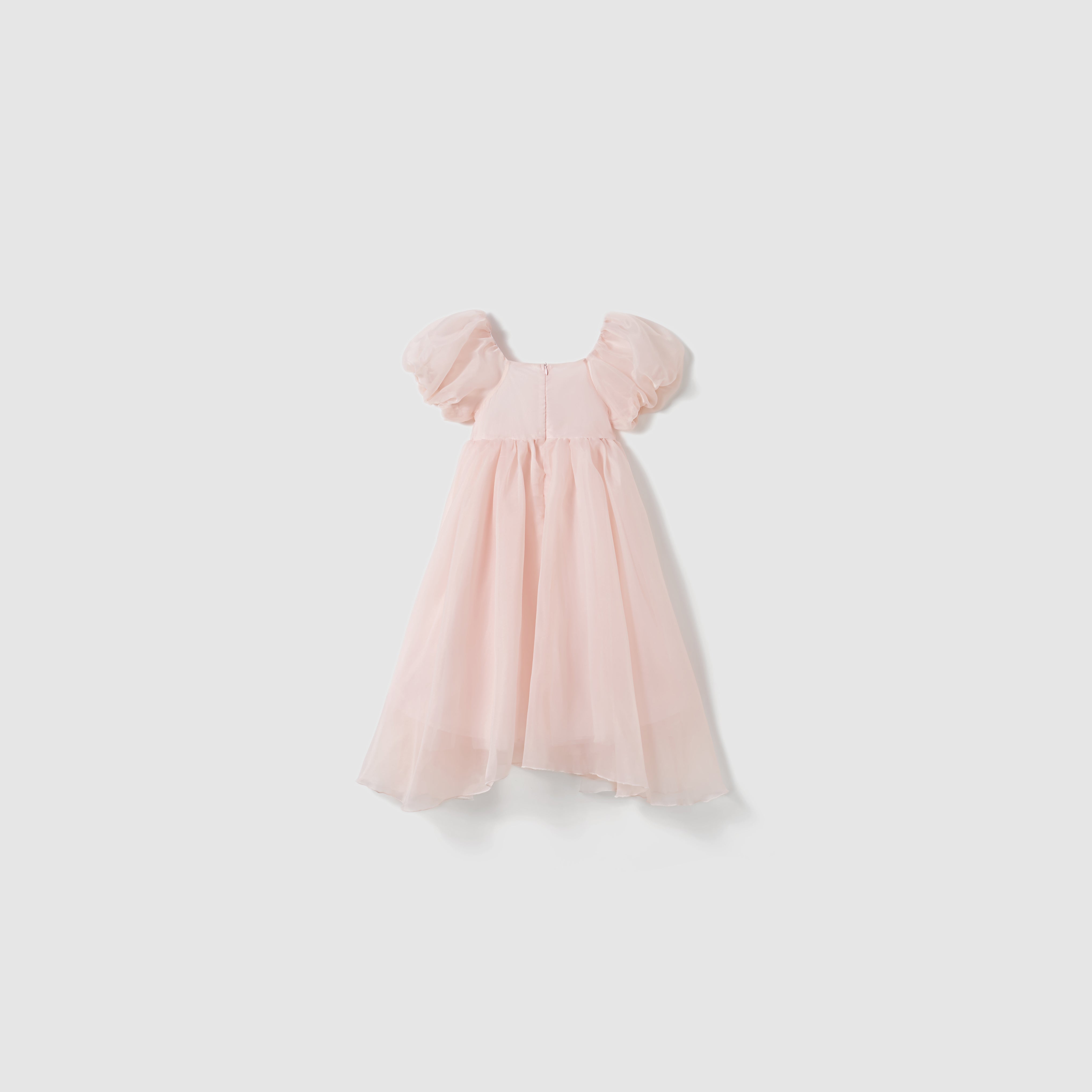The Blush Whisper Dress by KIKI and JOJO is a light pink, ankle-length, princess-style dress with short puff sleeves, a flowing skirt, and delicate 3D floral appliqués, shown on a plain white background.