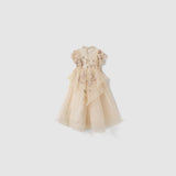 The Jade Whisper Dress by KIKI and JOJO is a cream, short-sleeved cheongsam with layered tulle, embroidered florals, and a high mandarin collar, shown against a plain white background.