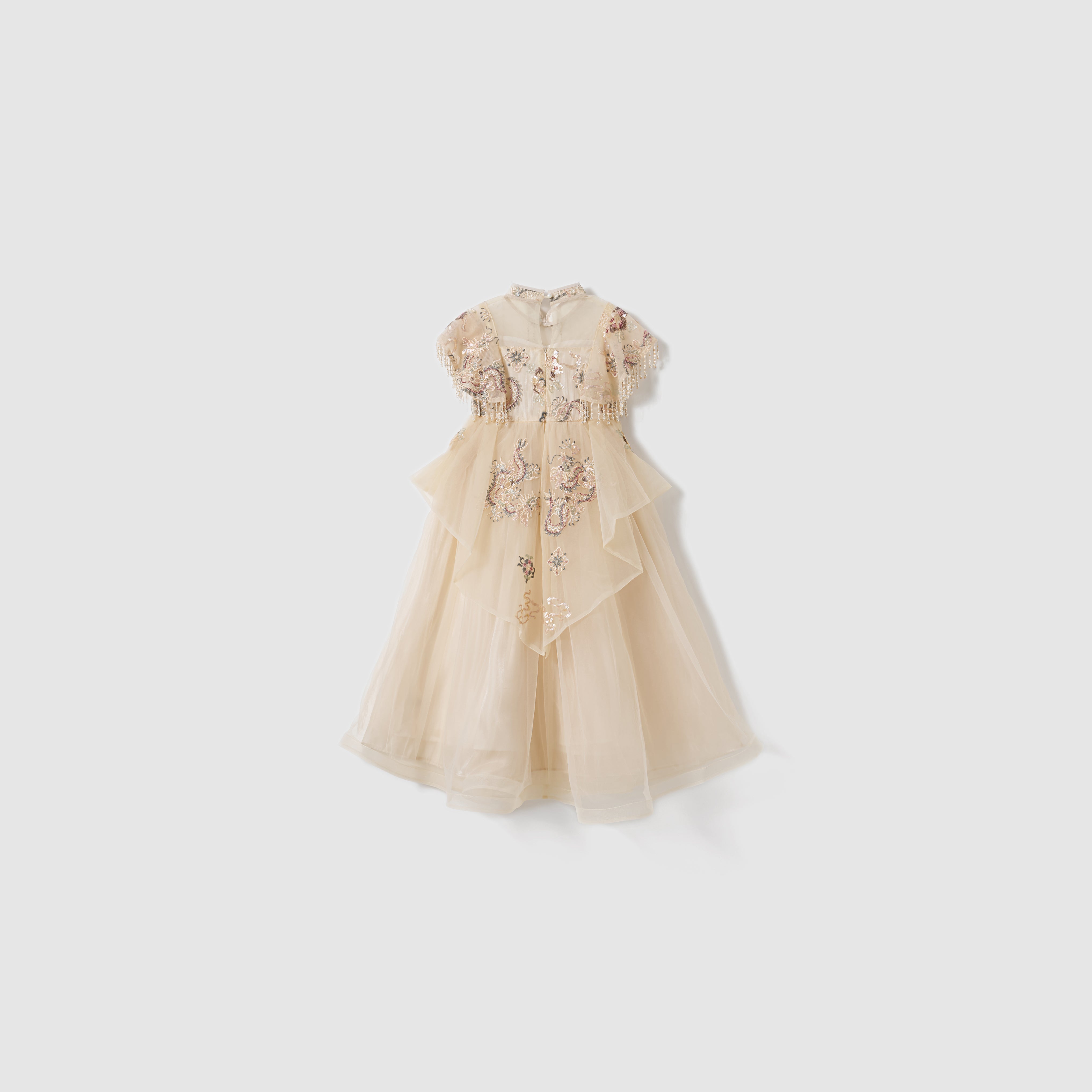 The Jade Whisper Dress by KIKI and JOJO is a cream, short-sleeved cheongsam with layered tulle, embroidered florals, and a high mandarin collar, shown against a plain white background.
