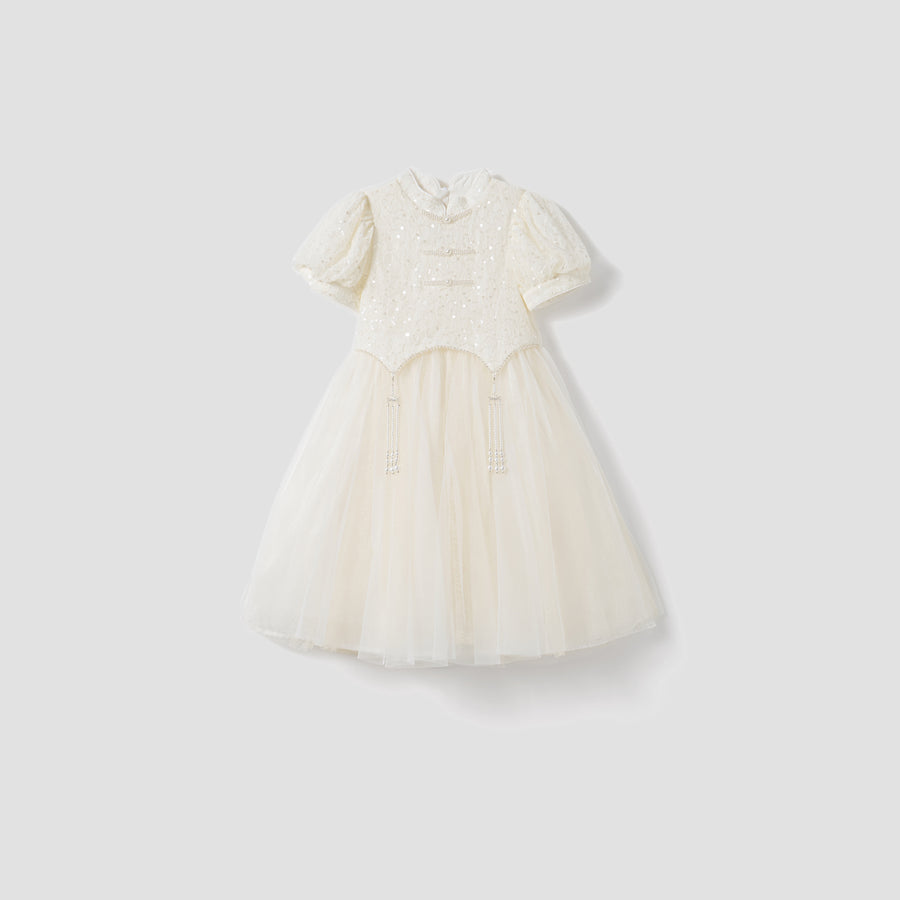 The Orchid Whisper Dress by KIKI and JOJO is a white, short-sleeved, knee-length modern vintage dress with a sequin-embroidered lace bodice, decorative buttons, and a tulle skirt, shown on a light gray background.