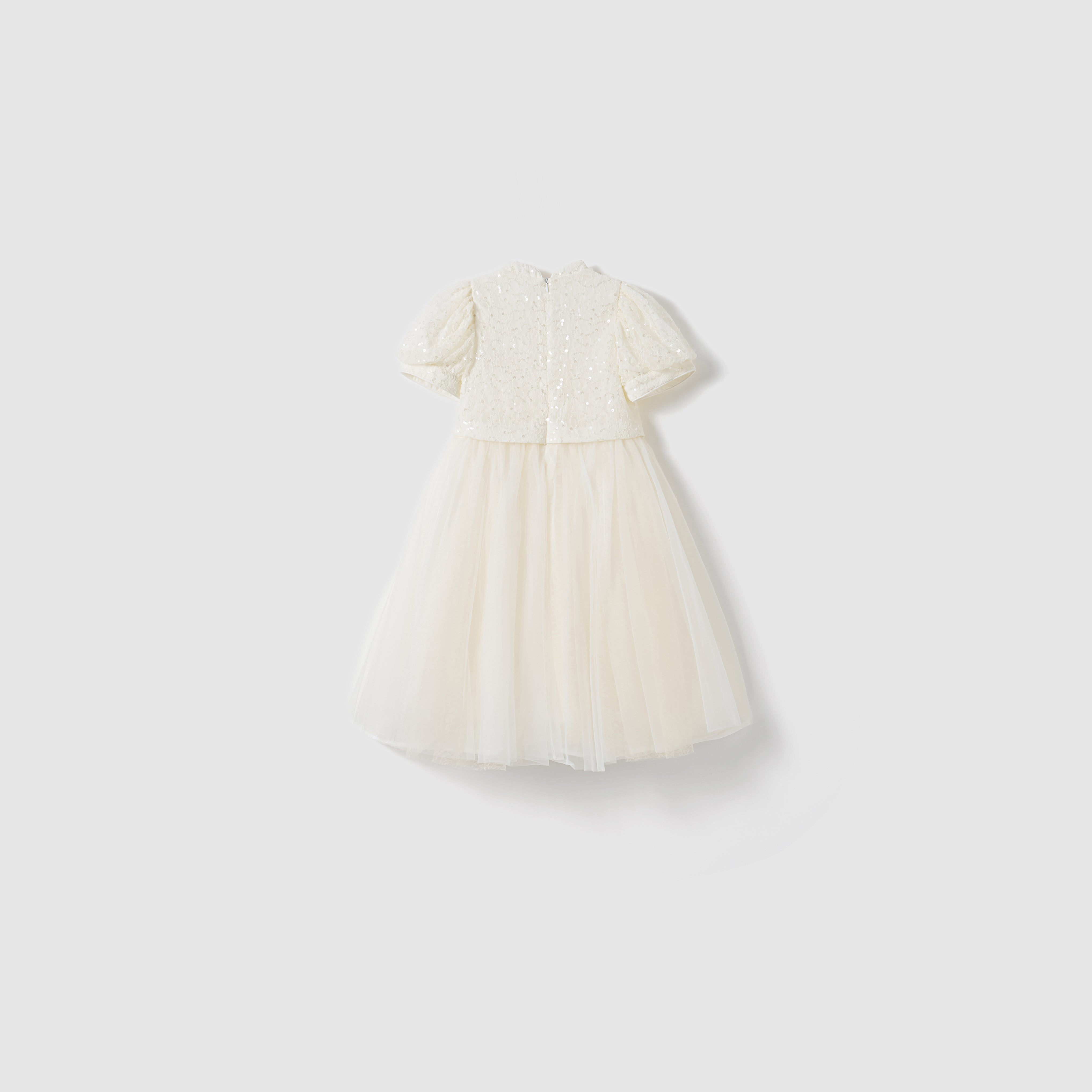The Orchid Whisper Dress by KIKI and JOJO is a white, short-sleeved girls’ knee-length dress with a sequin lace bodice and tulle skirt, shown against a plain light background.