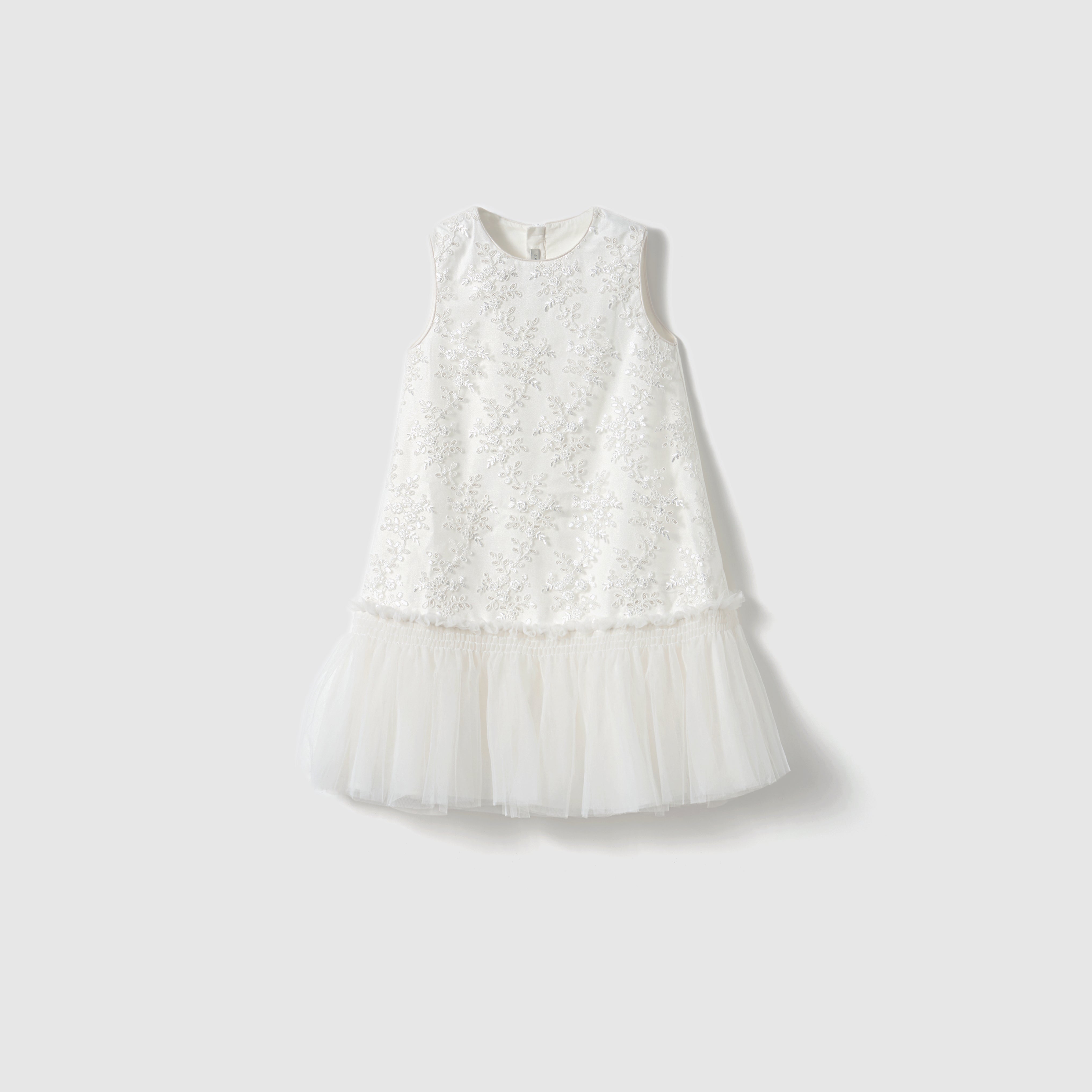The Twinkle Whisper Dress by KIKI and JOJO features a sleeveless white A-line design with an embroidered floral bodice and a tulle skirt, shown against a plain light background.