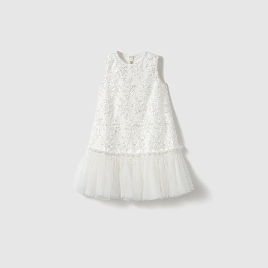 The Twinkle Whisper Dress by KIKI and JOJO features a sleeveless white A-line design with an embroidered floral bodice and a tulle skirt, shown against a plain light background.