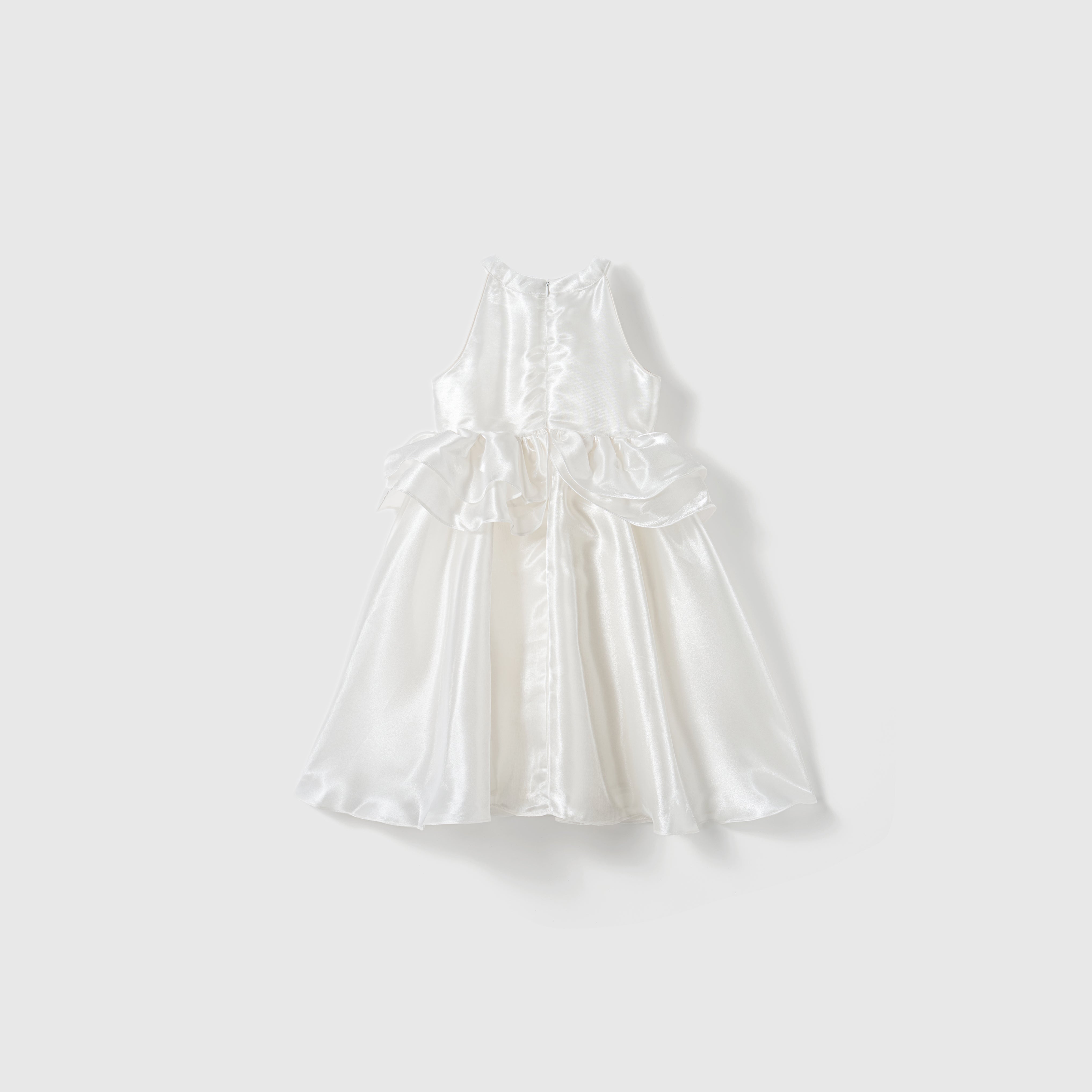 The Pearl Glow Whisper Dress by KIKI and JOJO is a sleeveless white satin A-line dress with a fitted bodice, flared skirt, and bow accents at the waist, shown against a plain light background.