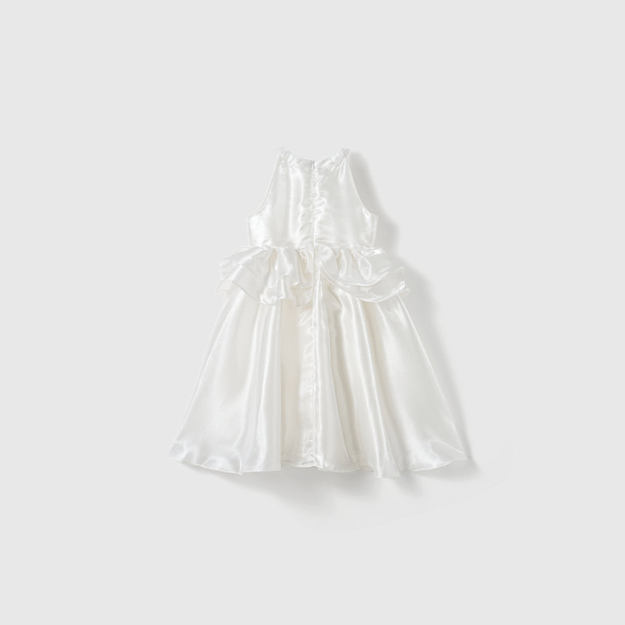 The Pearl Glow Whisper Dress by KIKI and JOJO is a sleeveless white satin A-line dress with a fitted bodice, flared skirt, and bow accents at the waist, shown against a plain light background.