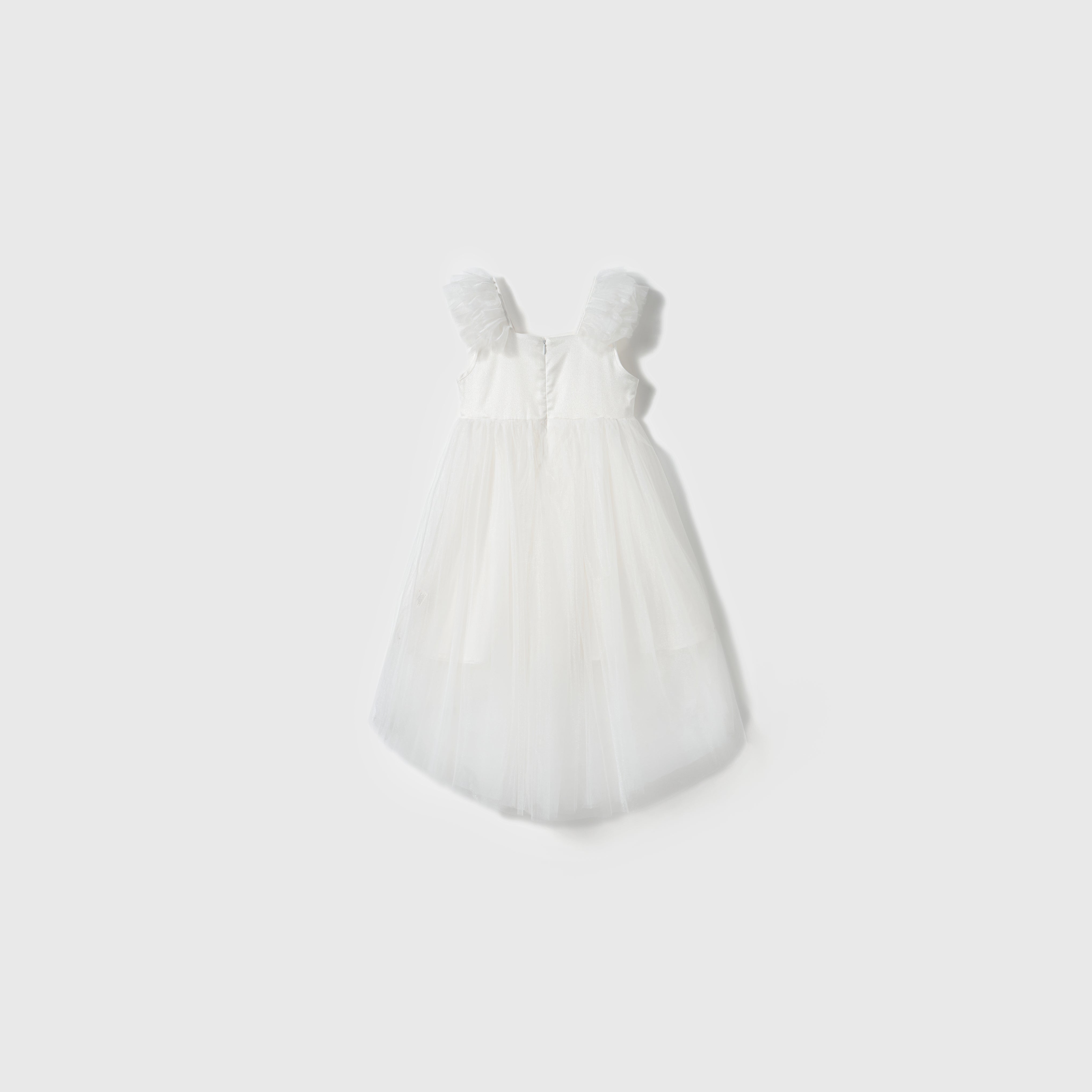 The Cloud Whisper Dress by KIKI and JOJO features ruffled shoulder straps and a flowy ivory tulle overlay, displayed against a plain light background.