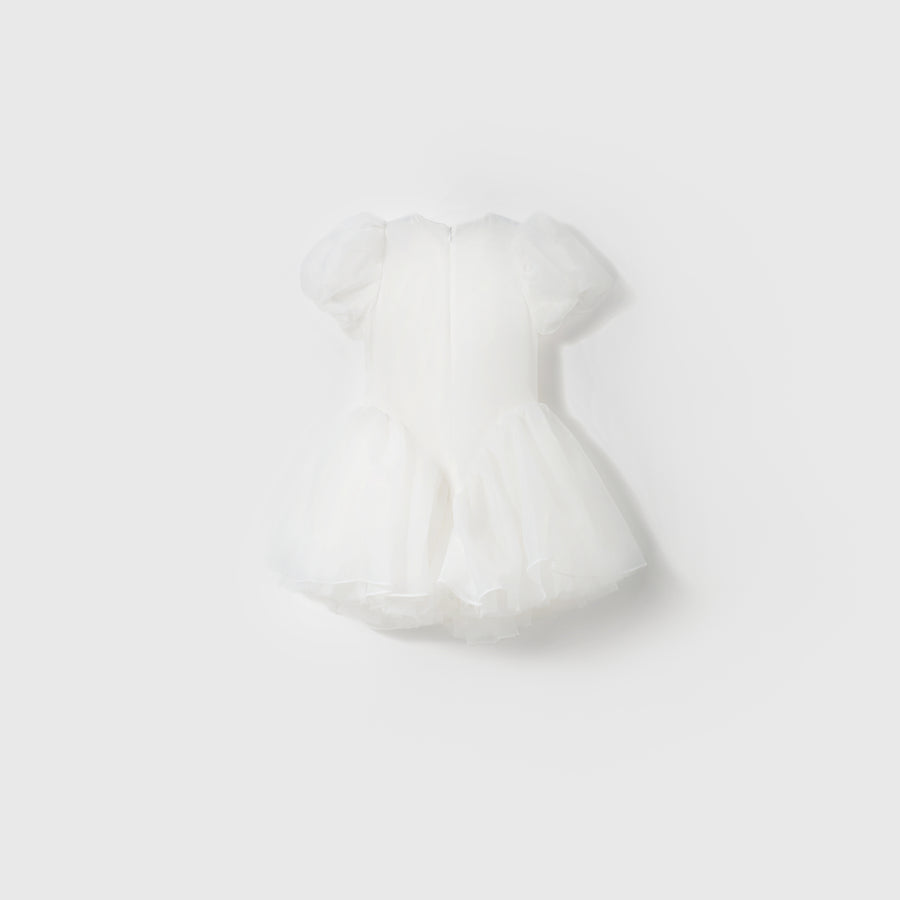 The Ballerina Whisper Dress by KIKI and JOJO is a white mini dress featuring short puffed sleeves, tulle fabric, and a flared skirt, showcased against a plain light background.