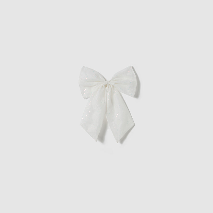 A large white fabric bow with subtle glitter details, inspired by the elegant Butterfly Whispers Dress from KIKI and JOJO, is displayed against a plain light gray background.