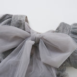 Close-up of a light gray sheer fabric bow on puffed sleeves, part of the elegant Dusk Whisper Dress by KIKI and JOJO, displayed against a plain white background.
