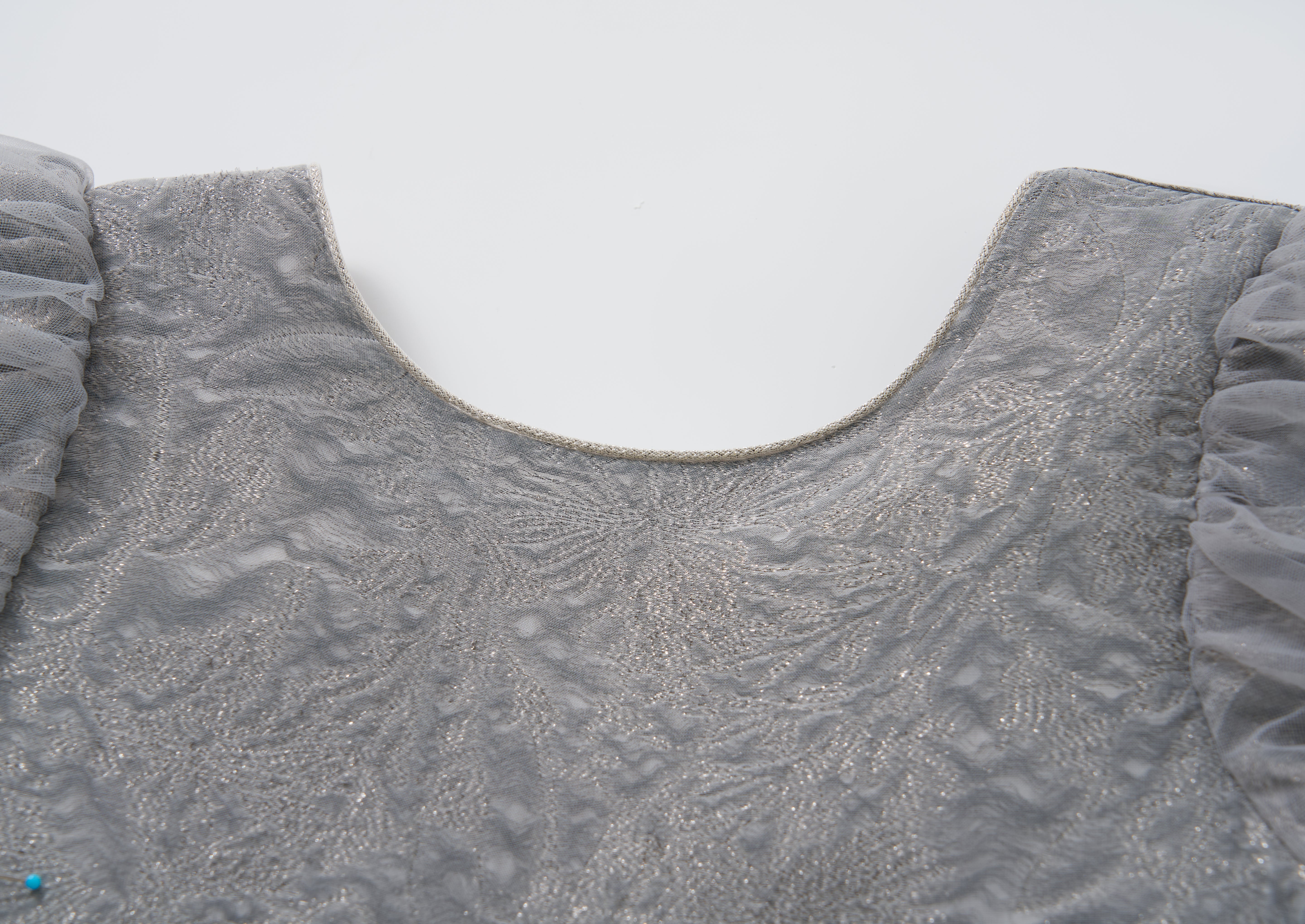 Close-up of the Dusk Whisper Dress by KIKI and JOJO, showcasing its textured grey fabric, tulle puff sleeves, and rounded neckline against a plain white background.
