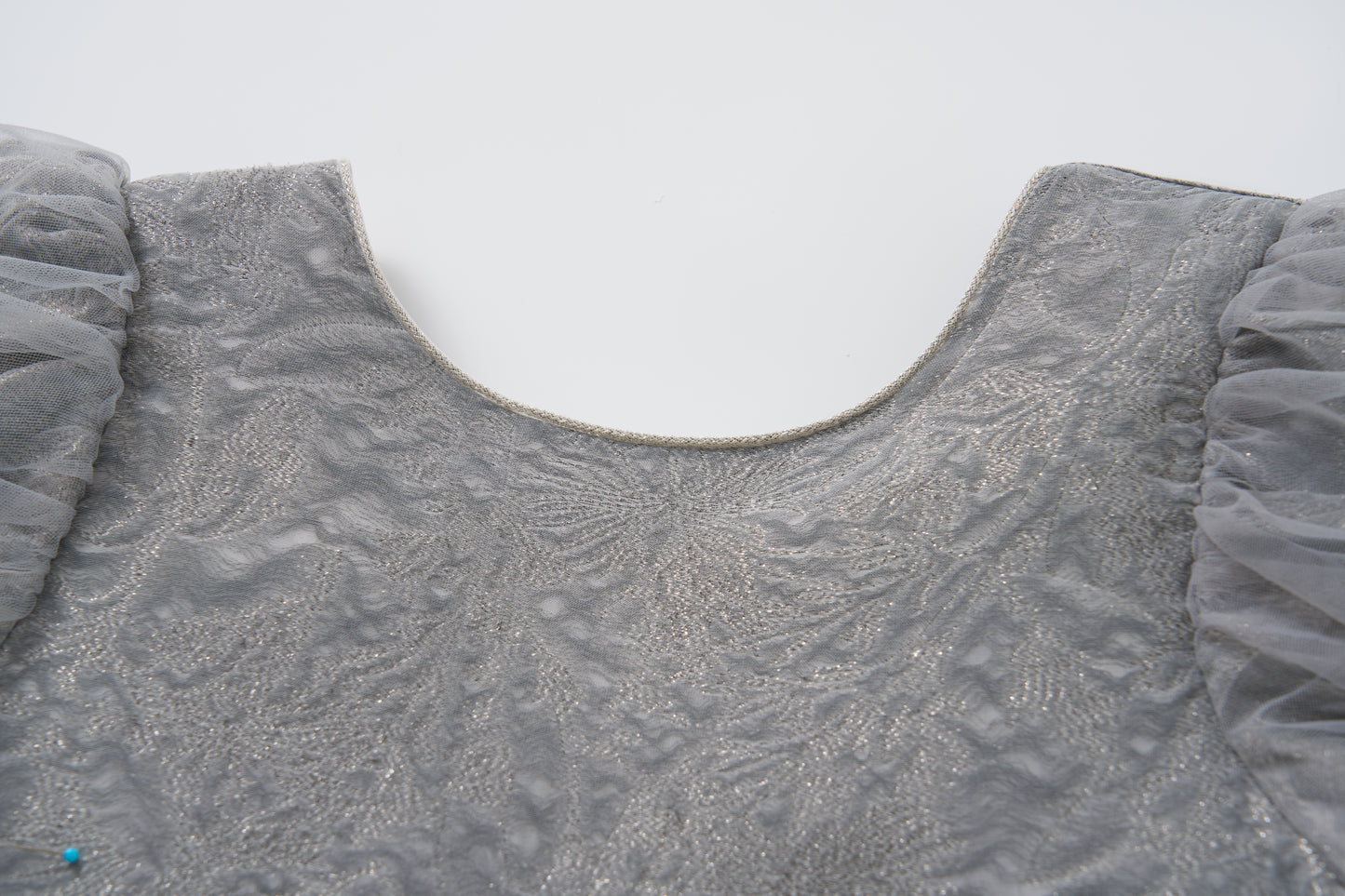 Close-up of the Dusk Whisper Dress by KIKI and JOJO, showcasing its textured grey fabric, tulle puff sleeves, and rounded neckline against a plain white background.