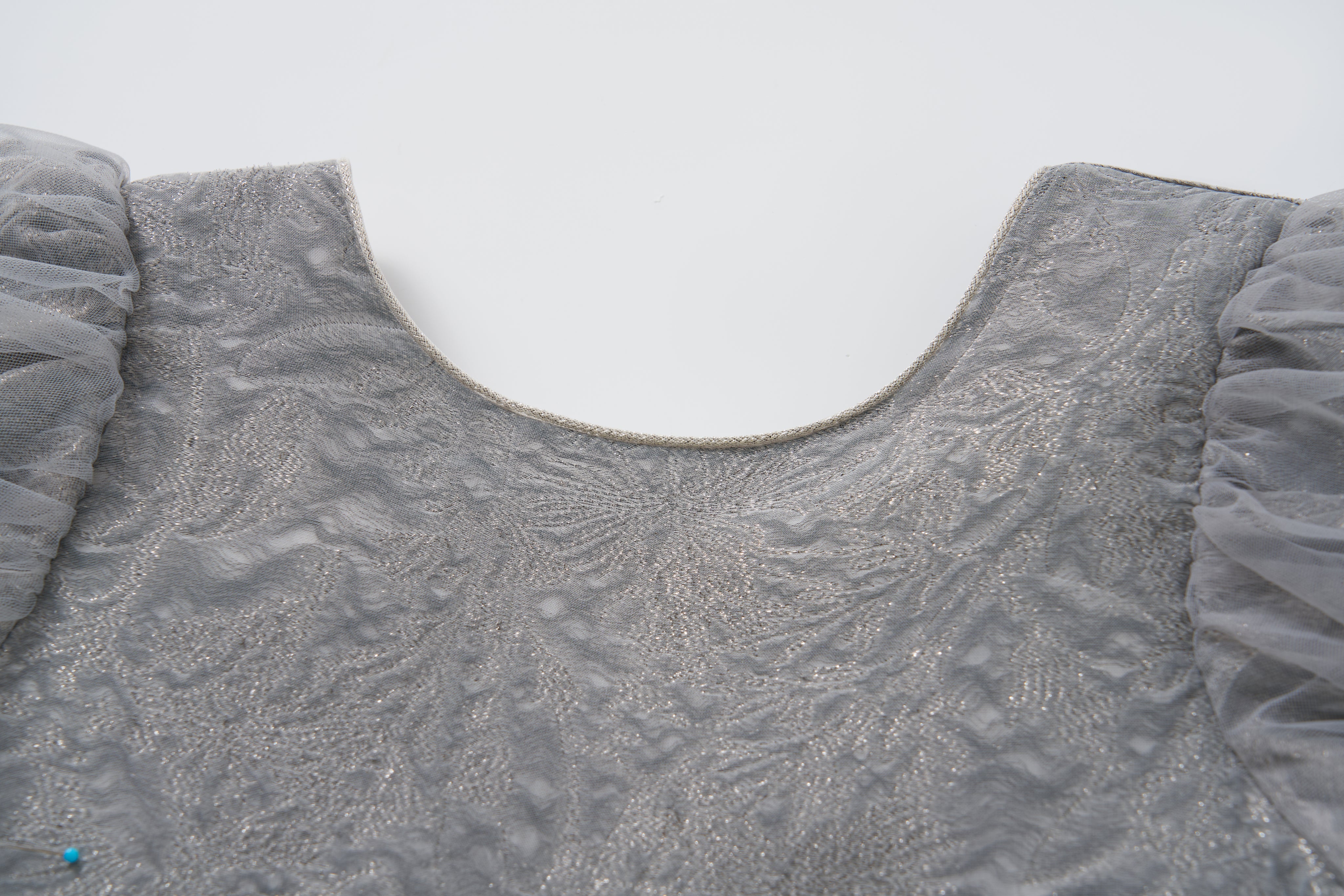 Close-up of the Dusk Whisper Dress by KIKI and JOJO, featuring a grey puff-sleeve design with a scoop neckline and sheer ruffled sleeves, displayed on a white background.