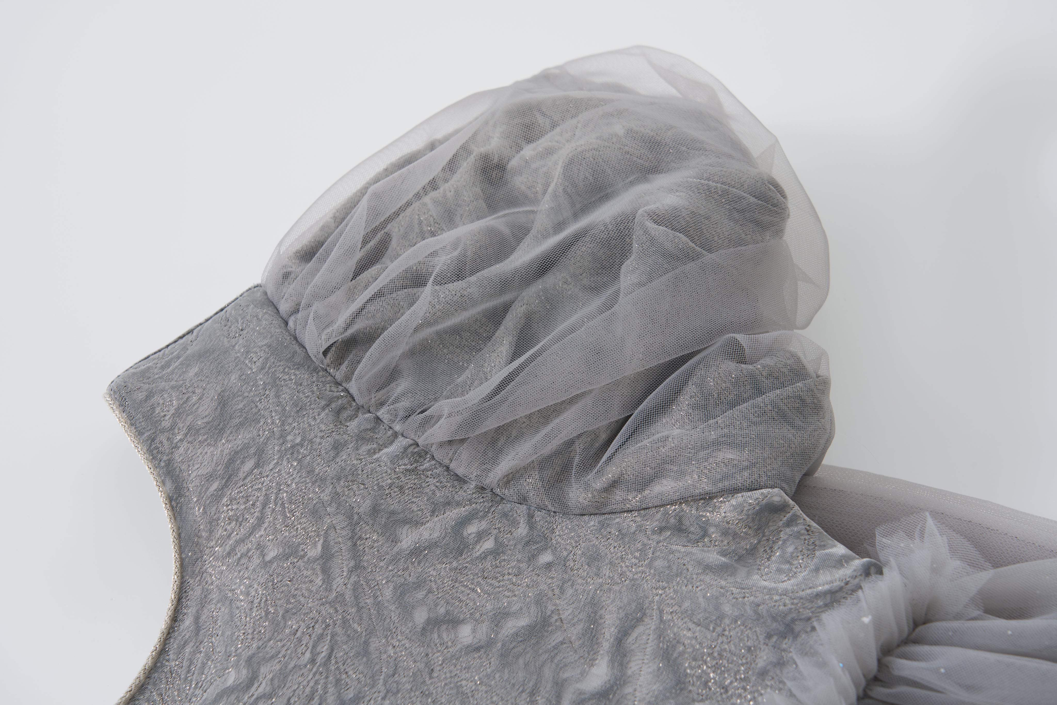 Close-up of the Dusk Whisper Dress by KIKI and JOJO in glittering silver tulle, featuring a textured bodice and sheer, voluminous puff sleeves against a plain white background.