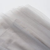 A close-up of soft, sheer light gray fabric with subtle glittery specks, draped in layers against a white background—ideal for creating the enchanting Dusk Whisper Dress by KIKI and JOJO.