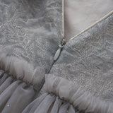 Close-up of the Dusk Whisper Dress by KIKI and JOJO, showcasing glittering silver tulle fabric, delicate tulle ruffles, and a partially unzipped silver zipper at the back.