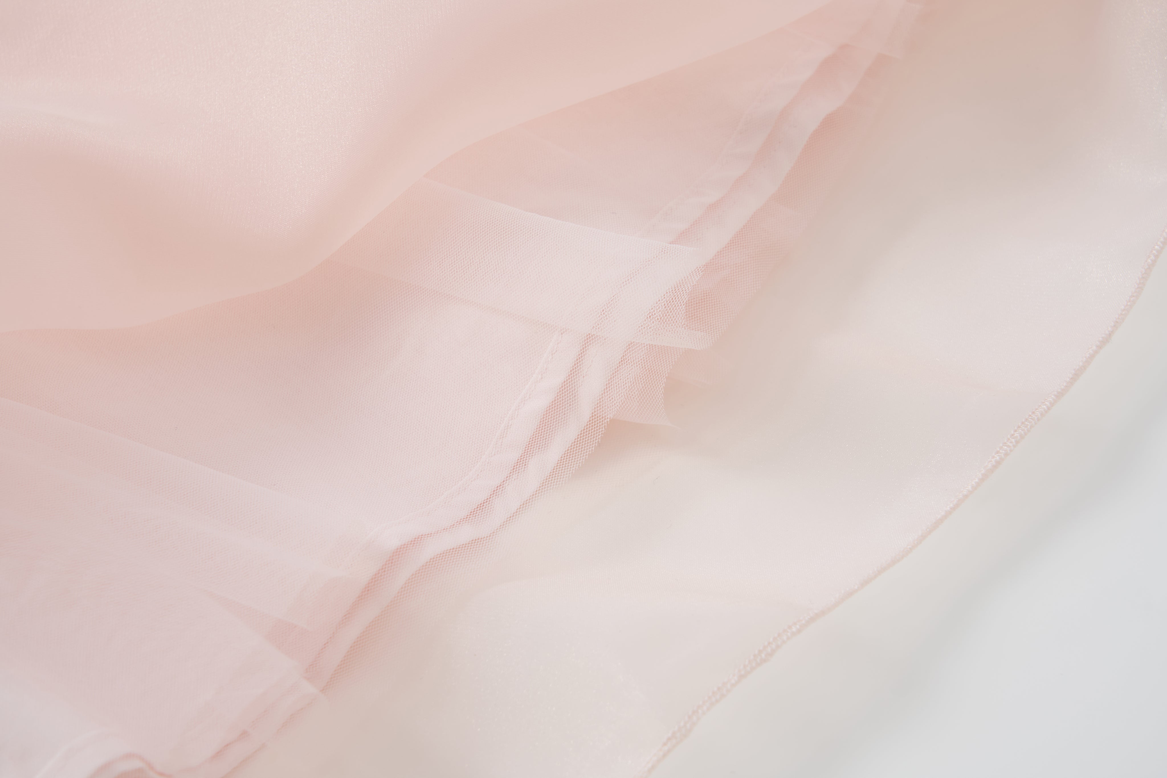 Close-up of the Blush Whisper Dress by KIKI and JOJO, featuring light pink sheer layers with soft folds and a slightly translucent look, perfect for princess-style outfits or embellished with delicate 3D floral appliqués.